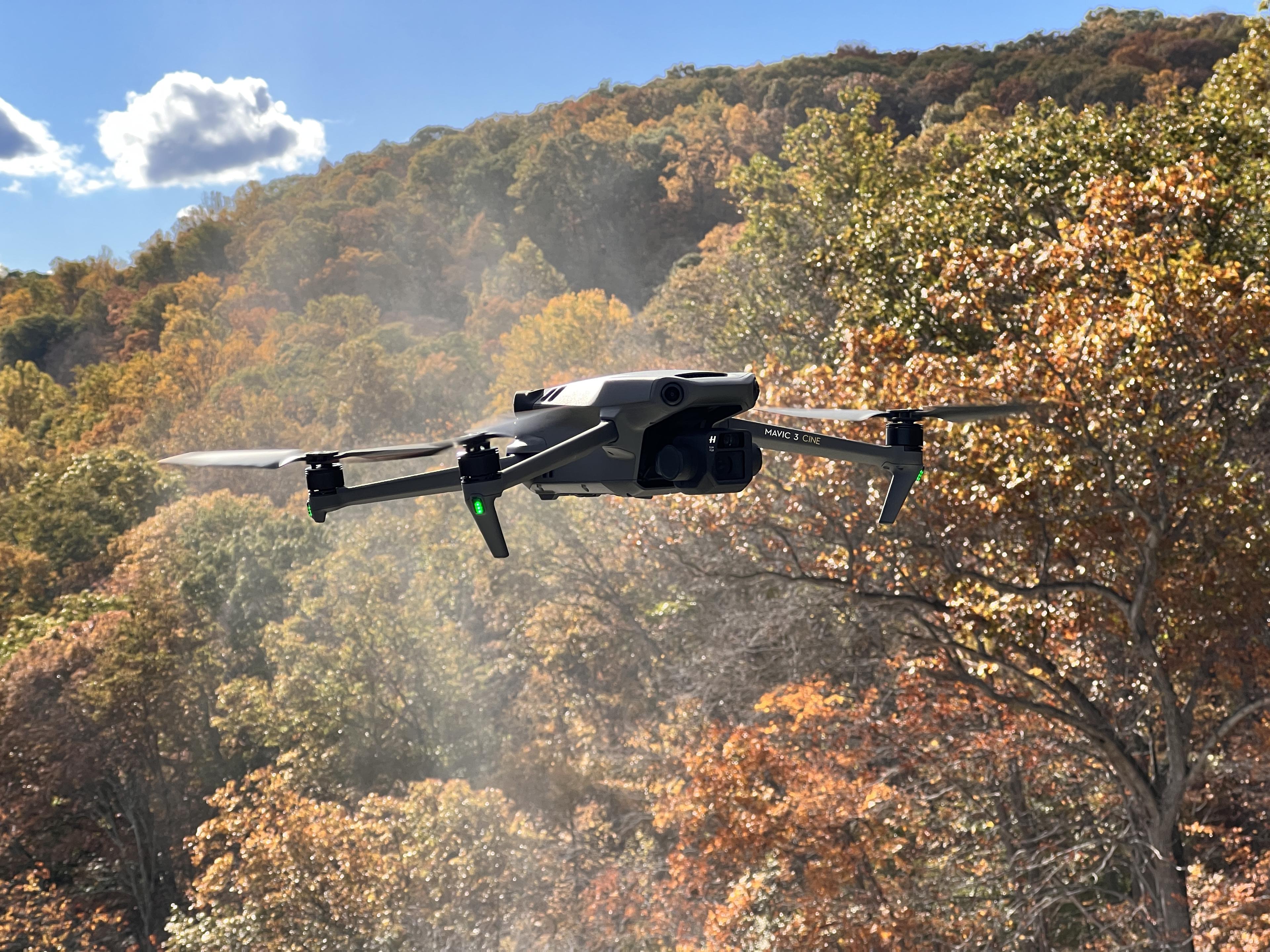 Real equipment reference photograph of a DJI Mavic 3 quadcopter in flight against autumn trees in New York, USA.