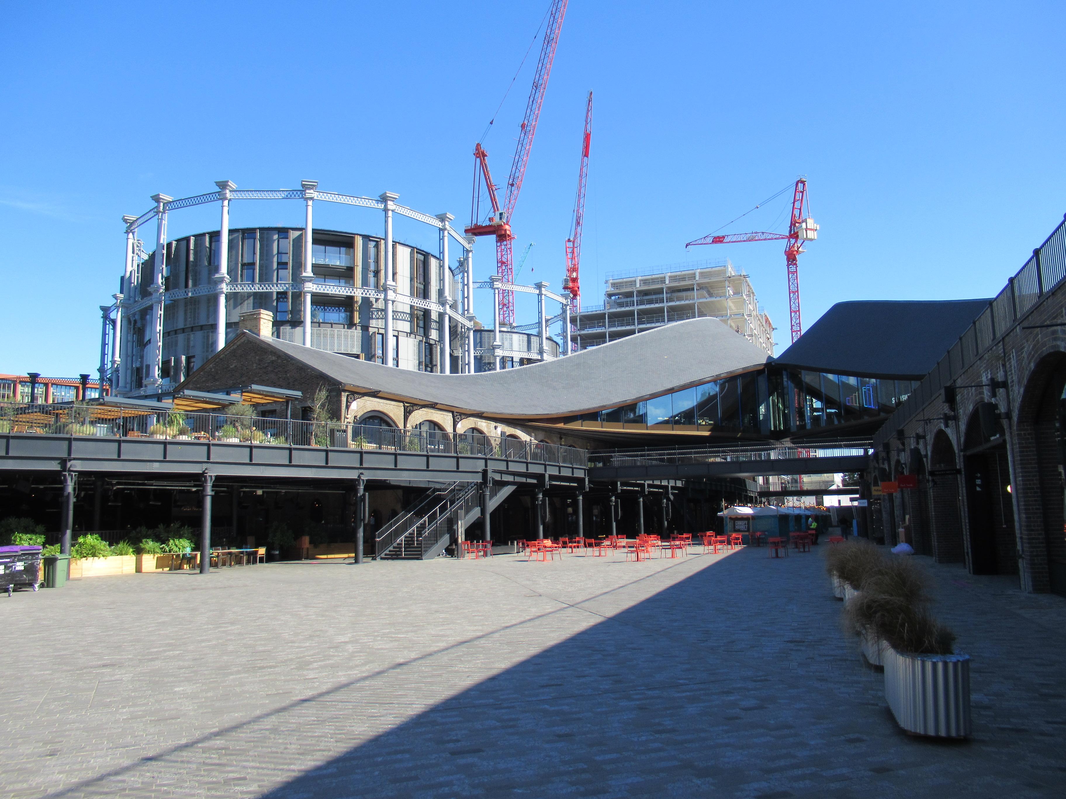 Real photograph of Coal Drops Yard in King’s Cross, London, showing adapted brick railway buildings, contemporary roof forms, public space and adjoining development.