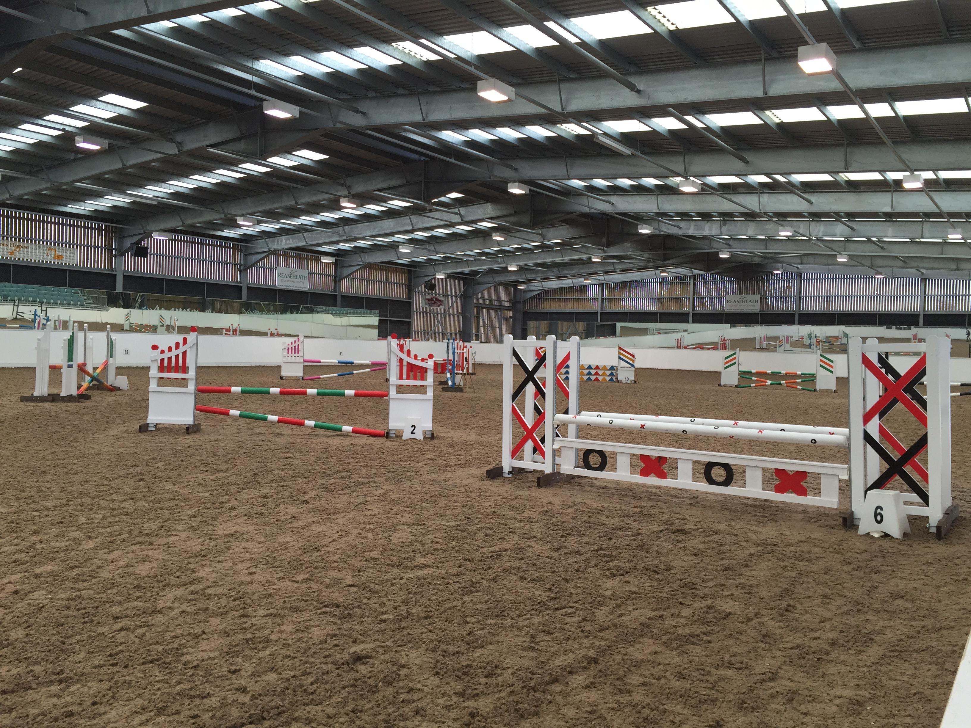 Indoor equestrian training arena at Reaseheath with show-jumping fences, riding surface and a clear-span roof.