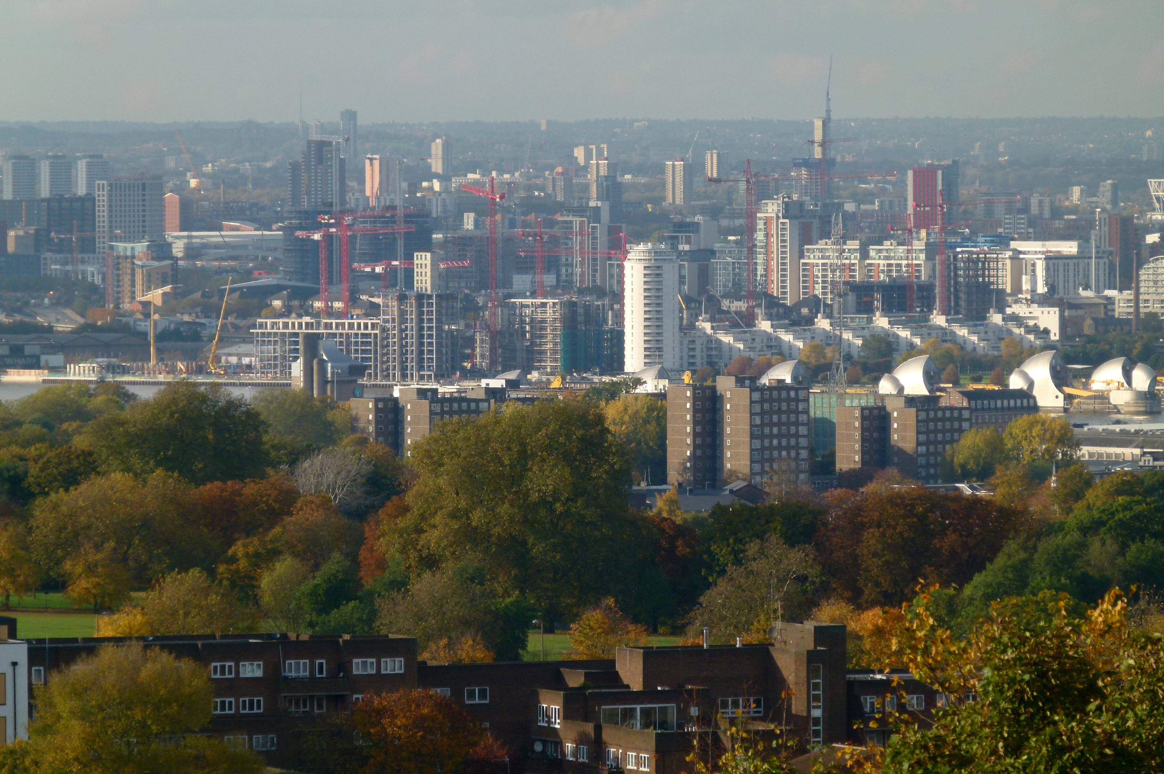 Real photograph of Royal Wharf under construction in 2015, showing residential buildings, multiple tower cranes and the wider Silvertown waterfront setting in London.
