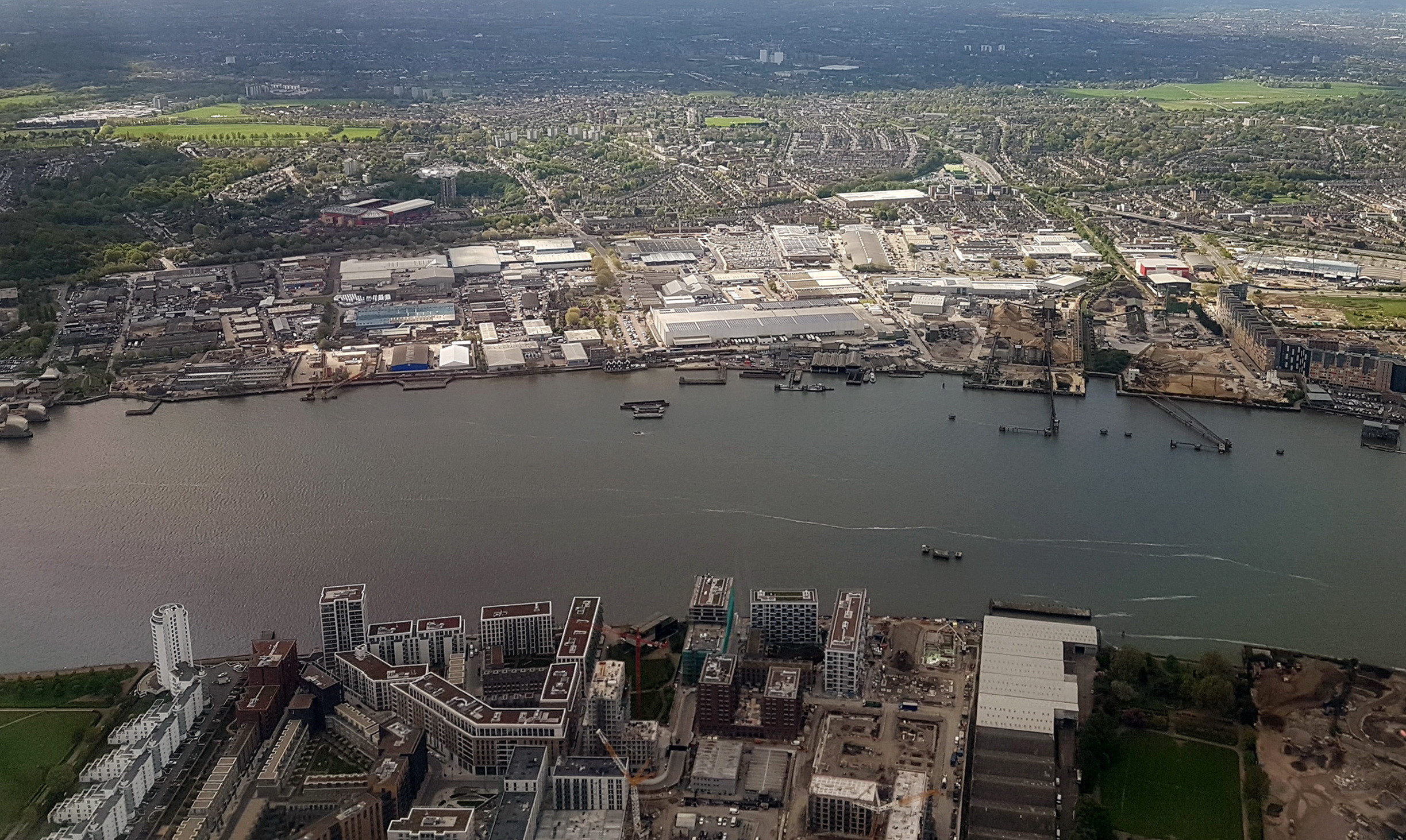 Real aerial reference photograph of Royal Wharf, the River Thames and Charlton Riverside in London, showing commercial buildings, industry and urban development.