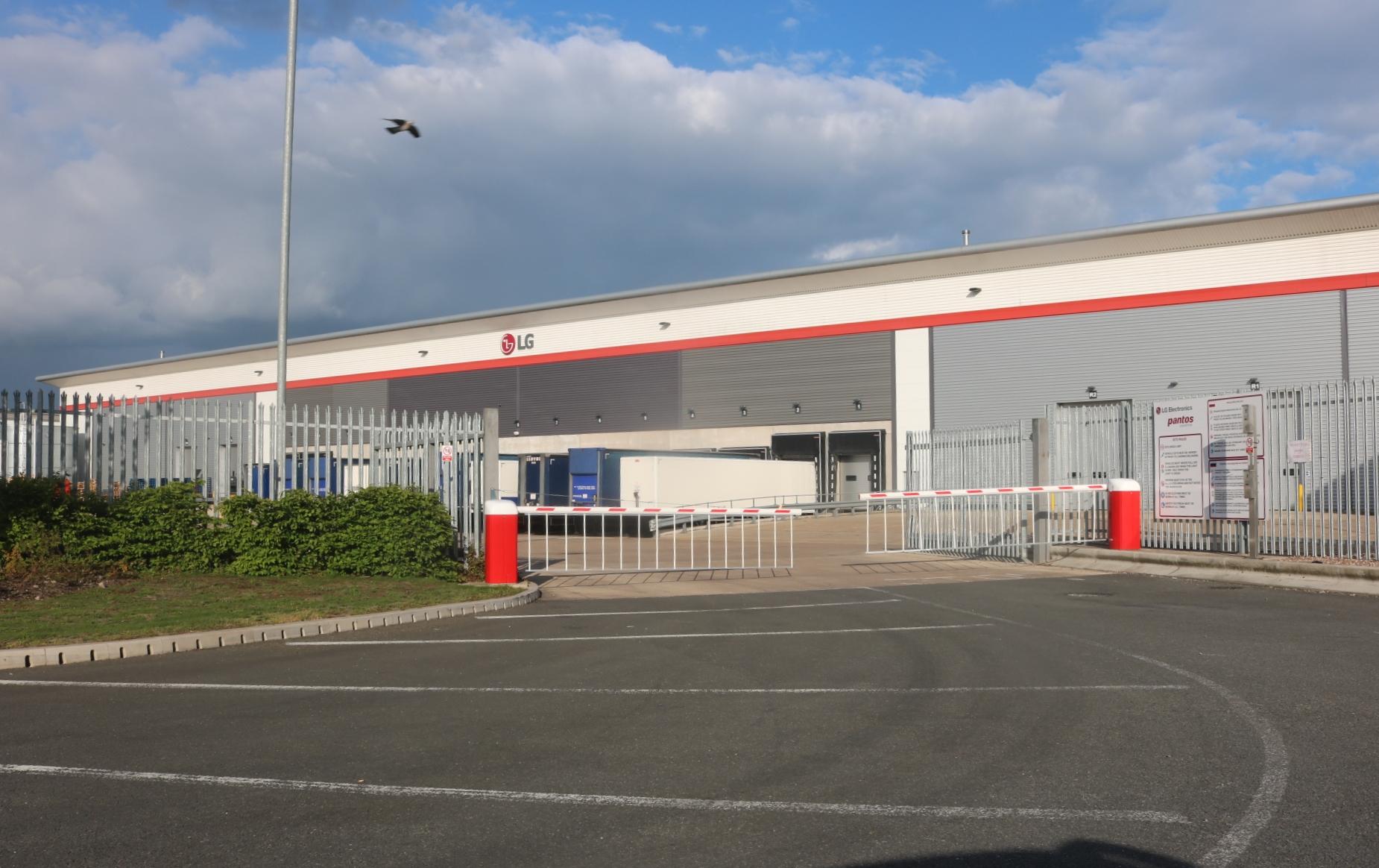 Real photograph of the LG warehouse at Prologis Park Ryton in Warwickshire, showing a substantial industrial building, office frontage, access road and landscaped site edge.
